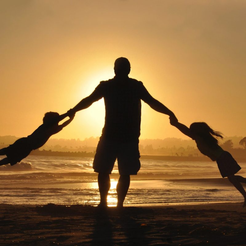 Father plays with children at a family gathering on a beach in Sicily